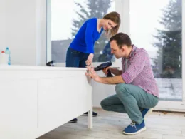 Kobieta pomaga mężczyźnie skręcać szafki do łazienki